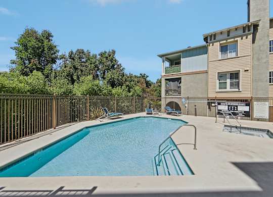 A swimming pool in front of a building with a fence around it.