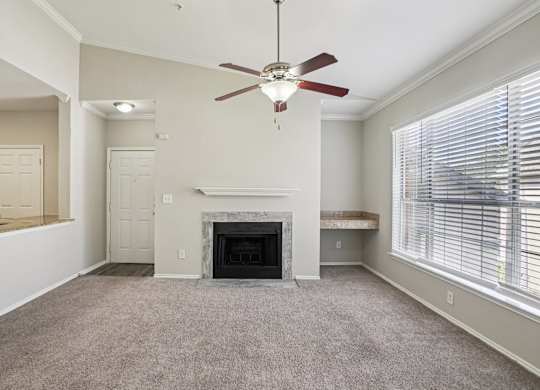 A living room with a fireplace and a ceiling fan.