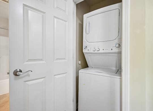 A white door is open to reveal a white microwave and oven.