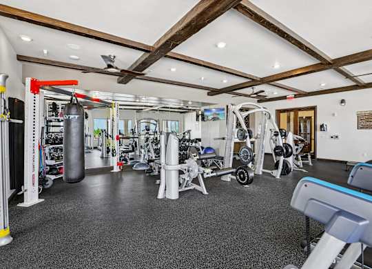 A gym with a variety of equipment including a punching bag, weight bench and leg press machine.