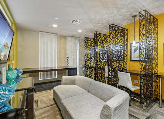 A living room with a grey couch and a yellow wall.