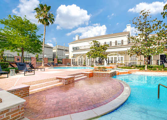 A swimming pool surrounded by a brick patio and a building in the background.