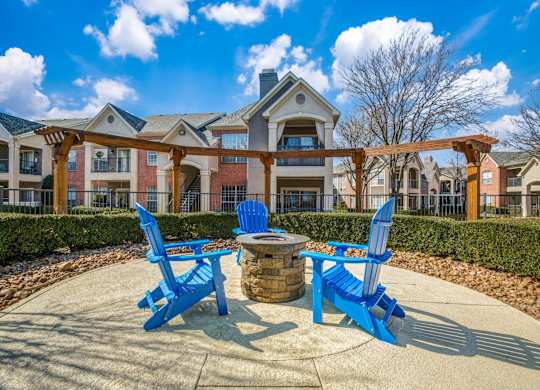 Two blue chairs and a table are in the foreground of a building.