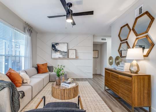 A living room with a grey couch, a wooden coffee table, and a ceiling fan.