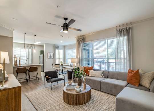 A living room with a grey couch, a wooden coffee table, and a ceiling fan.