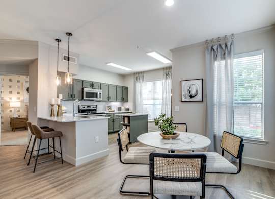 A kitchen with a table and chairs in front of a window.