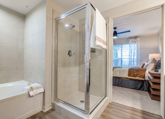 A bathroom with a glass shower door and a white bathtub.