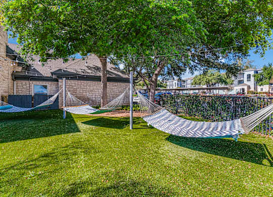 two hammocks on the grass in front of a house