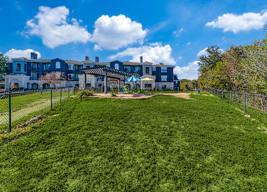 a yard with a fence and houses in the background