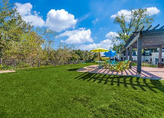 a backyard with a patio with chairs and umbrellas