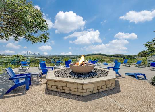 a fire pit with blue chairs and a view of the city
