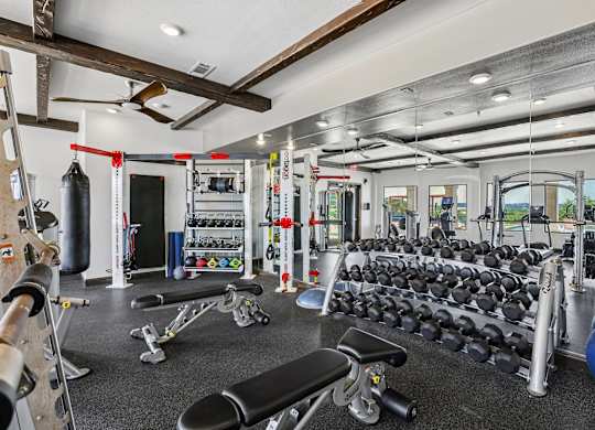 A gym with a variety of equipment including dumbbells, weight machines, and a bench press.