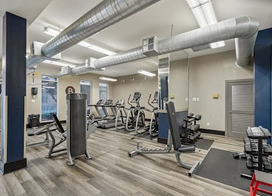 A gym with a variety of equipment including treadmills, weights, and exercise machines.