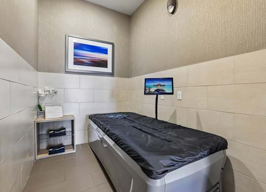 A room with a bed and a small TV mounted on the wall.