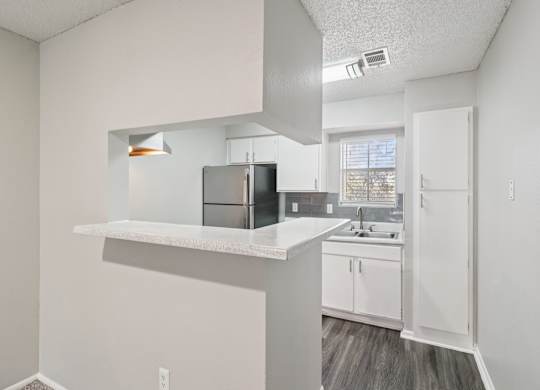 A kitchen with white cabinets and a black refrigerator.