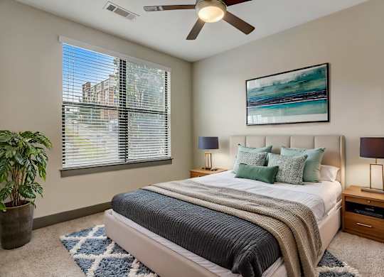 Nashville Apartments - Octave Apartments - Bedroom with plush carpet, ceiling fan, and large windows with natural light