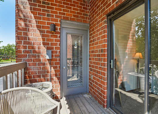 A patio with a chair and a table is visible through a glass door.