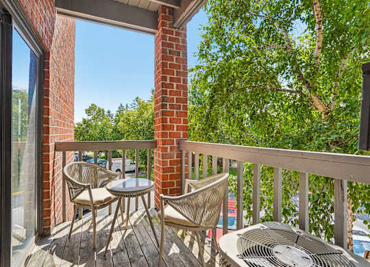 A patio with a table and chairs overlooking a tree.