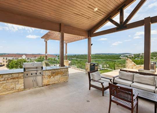 A patio with a grill and seating area overlooking a city.