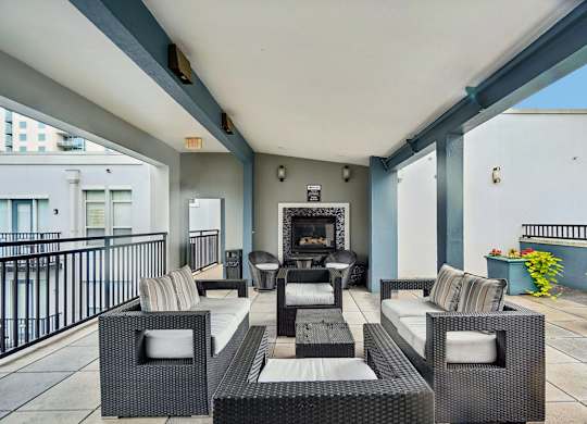 A patio with a black wicker sofa and a fireplace.