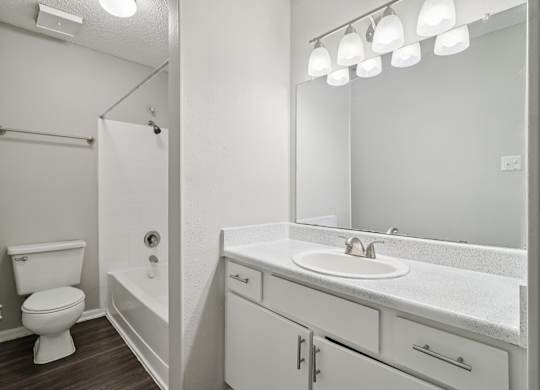 A white bathroom with a toilet, sink, and mirror.