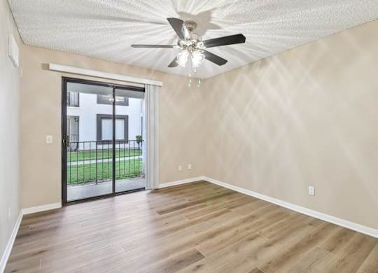 A room with a ceiling fan and sliding glass doors.