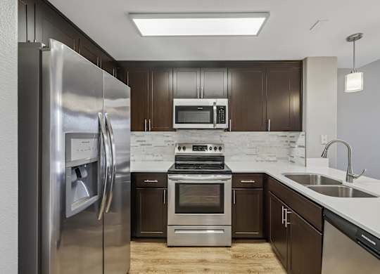 A modern kitchen with dark brown cabinets and stainless steel appliances.