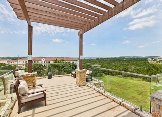 A wooden patio with a bench and a view of the countryside.