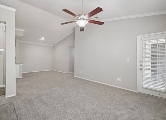 A room with a ceiling fan and carpeted floor.