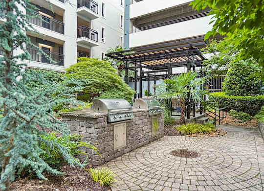 A small garden with a circular brick walkway and a small fountain in the middle.