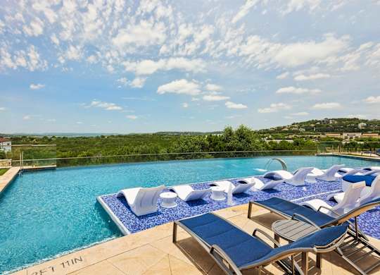 A large swimming pool with lounge chairs and a view of the countryside.