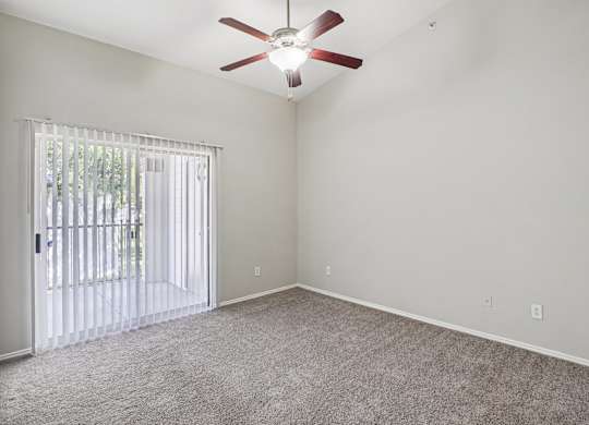 A room with a ceiling fan and a sliding glass door.