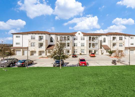 a large apartment building with cars parked in a parking lot