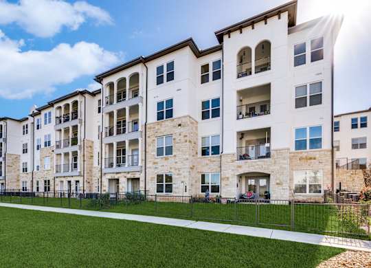 an image of an apartment building with green grass and a sidewalk