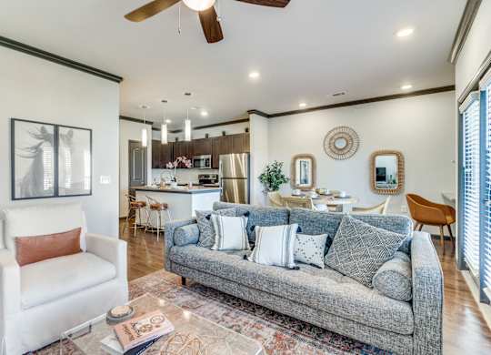 a living room with a couch and a chair in front of a kitchen