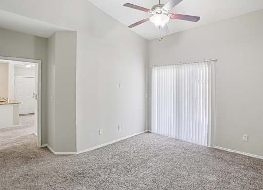 A room with a ceiling fan and carpeted floor.