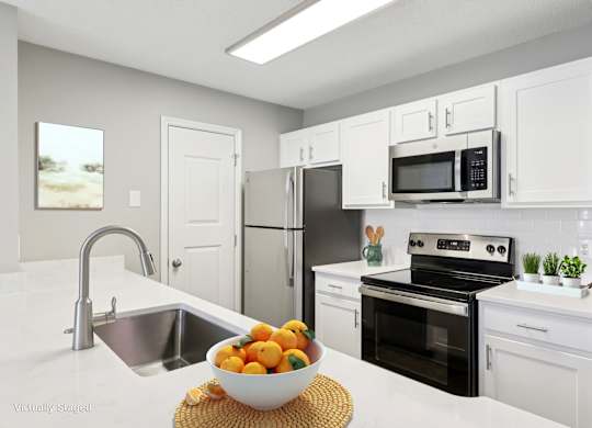 A kitchen with a bowl of oranges on the counter.