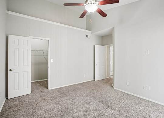 A room with a ceiling fan and carpeted floor.