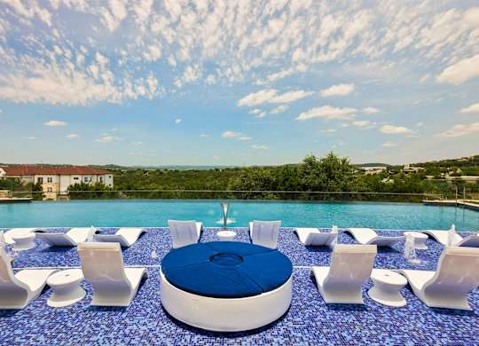 A poolside seating area with white chairs and a blue circular table.