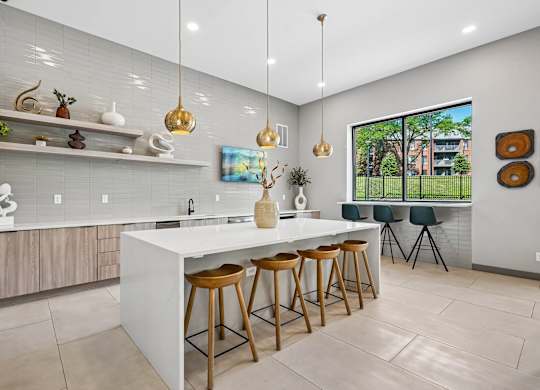 A modern kitchen with a white island and wooden stools.