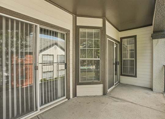 A patio with a sliding glass door and a metal railing.