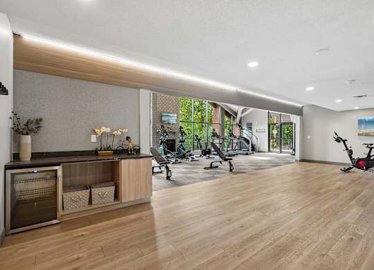 A spacious room with wooden floors and a variety of exercise equipment.