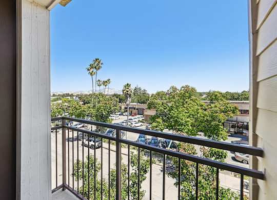 A balcony view of a parking lot and trees.