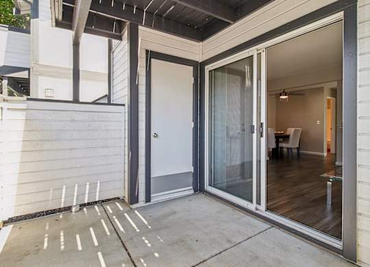 A patio with a glass door leading to a room.