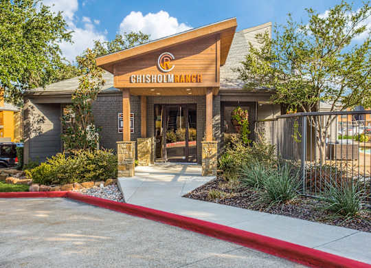 The Chisholm Ranch building has a wooden entrance with a red walkway leading to it.