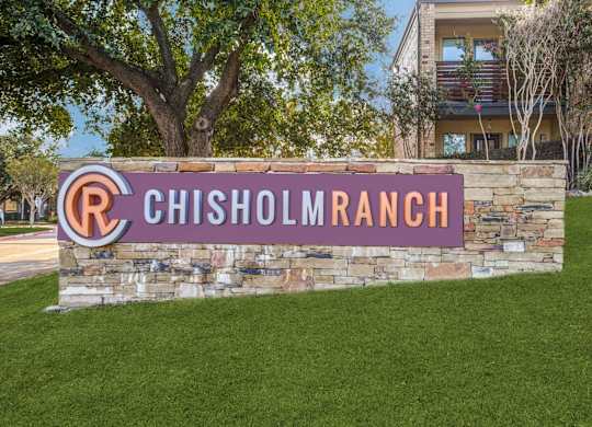 A sign that says Chisholm Ranch in front of a building.