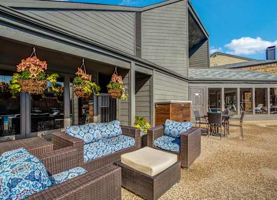 A patio area with a couch, chairs, and hanging flower baskets.