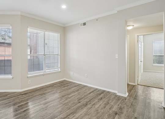 A room with wooden flooring and a window with blinds.