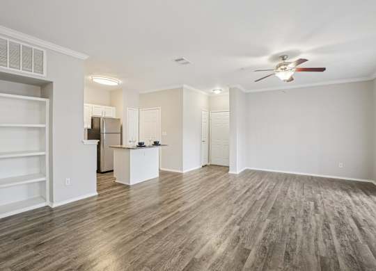 A spacious room with a ceiling fan and wooden flooring.