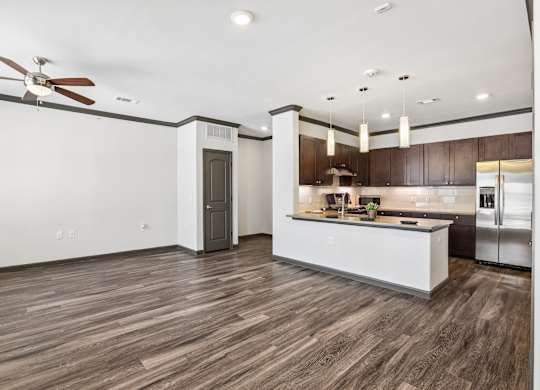 A modern kitchen with a white island and dark wood flooring.